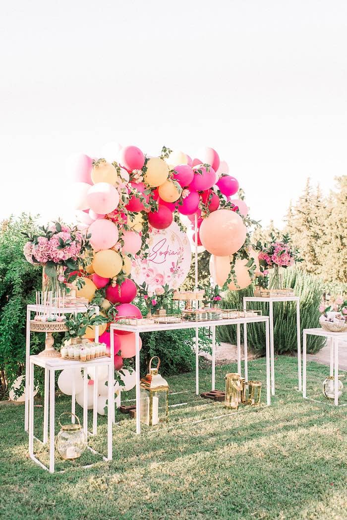 table with sweets elegantly set up with pink balloons and flowers