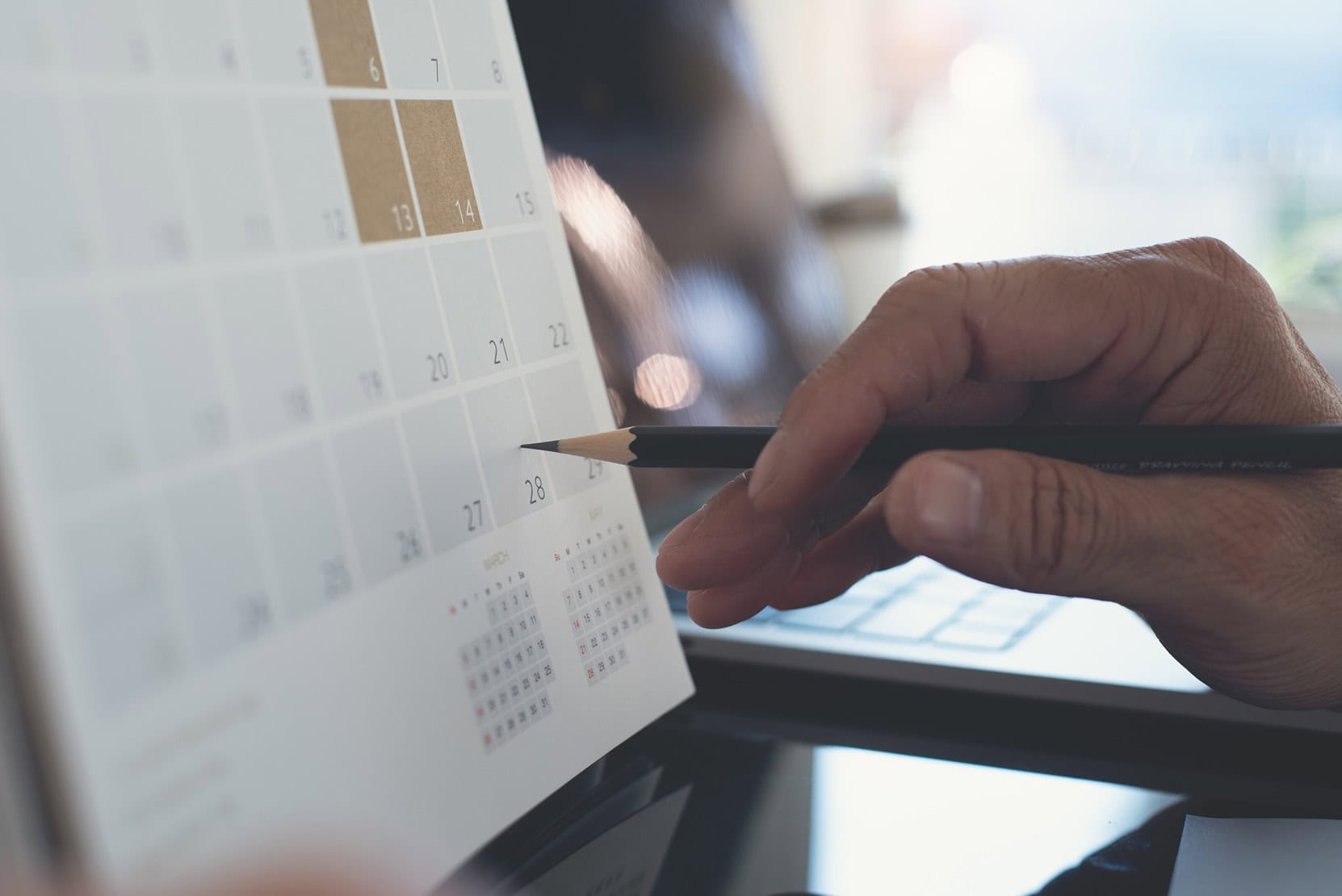 closeup of a person penciling in a date on a calendar