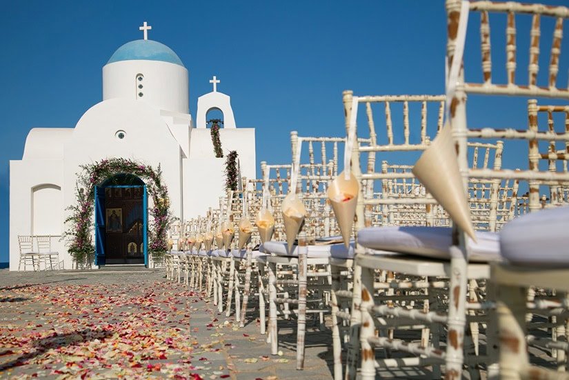 chairs decorated and flower petals around a Greek Orthodox church