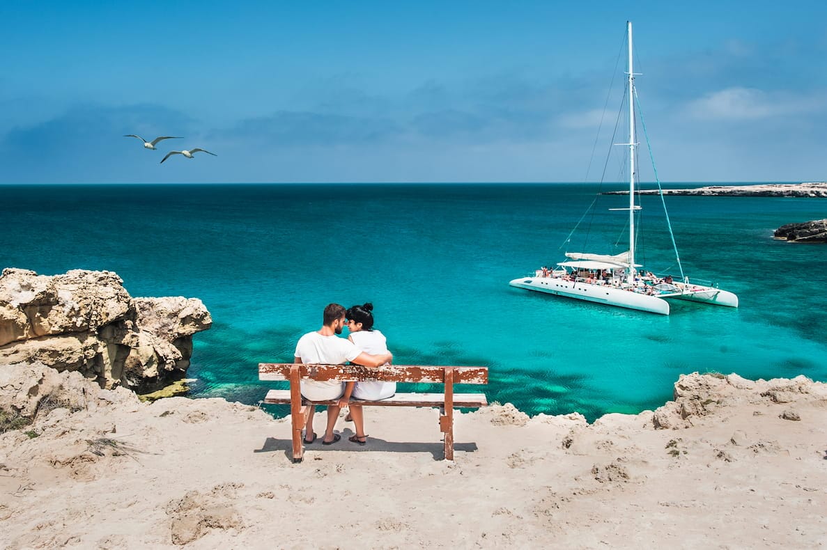 couple on a bench overlooking the sea and a private yacht