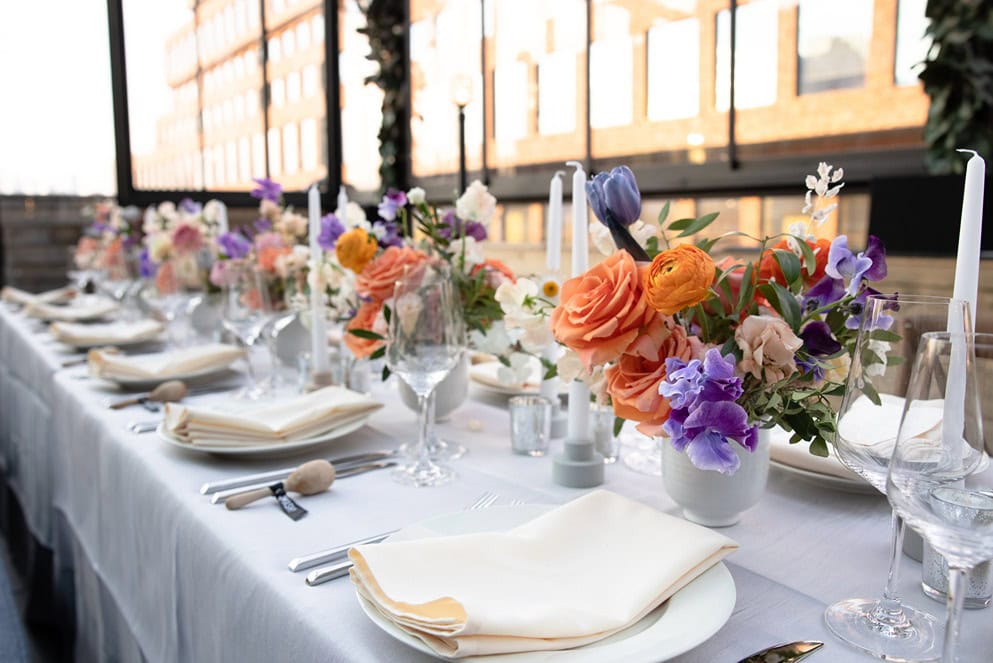 table elegantly set for an event with china and orange and purple bouquets