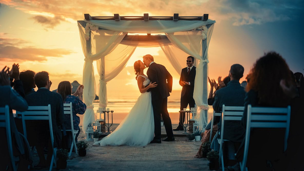 a couple kissing at the alter with the sun setting over the Mediterranean sea behind them
